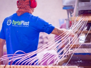 Homem ao lado da uma máquina com fios de plásticos